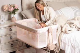 Baby bedside sleeper bassinet in pink with height adjustment and storage basket